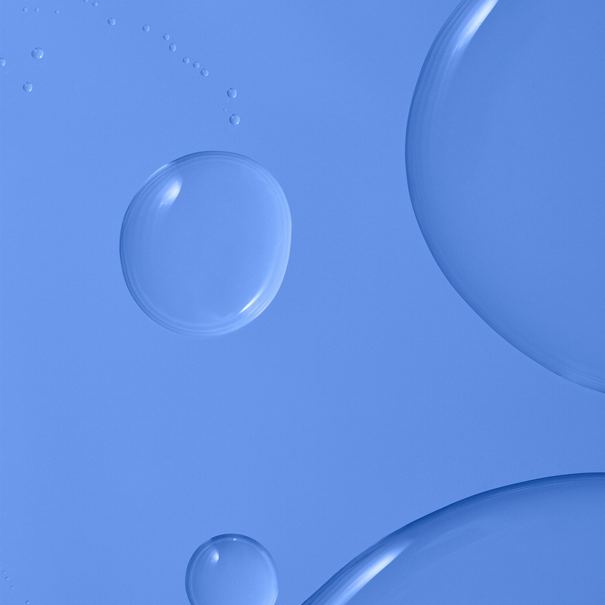Clear, round skincare serum droplets of varying sizes scattered across a blue background.