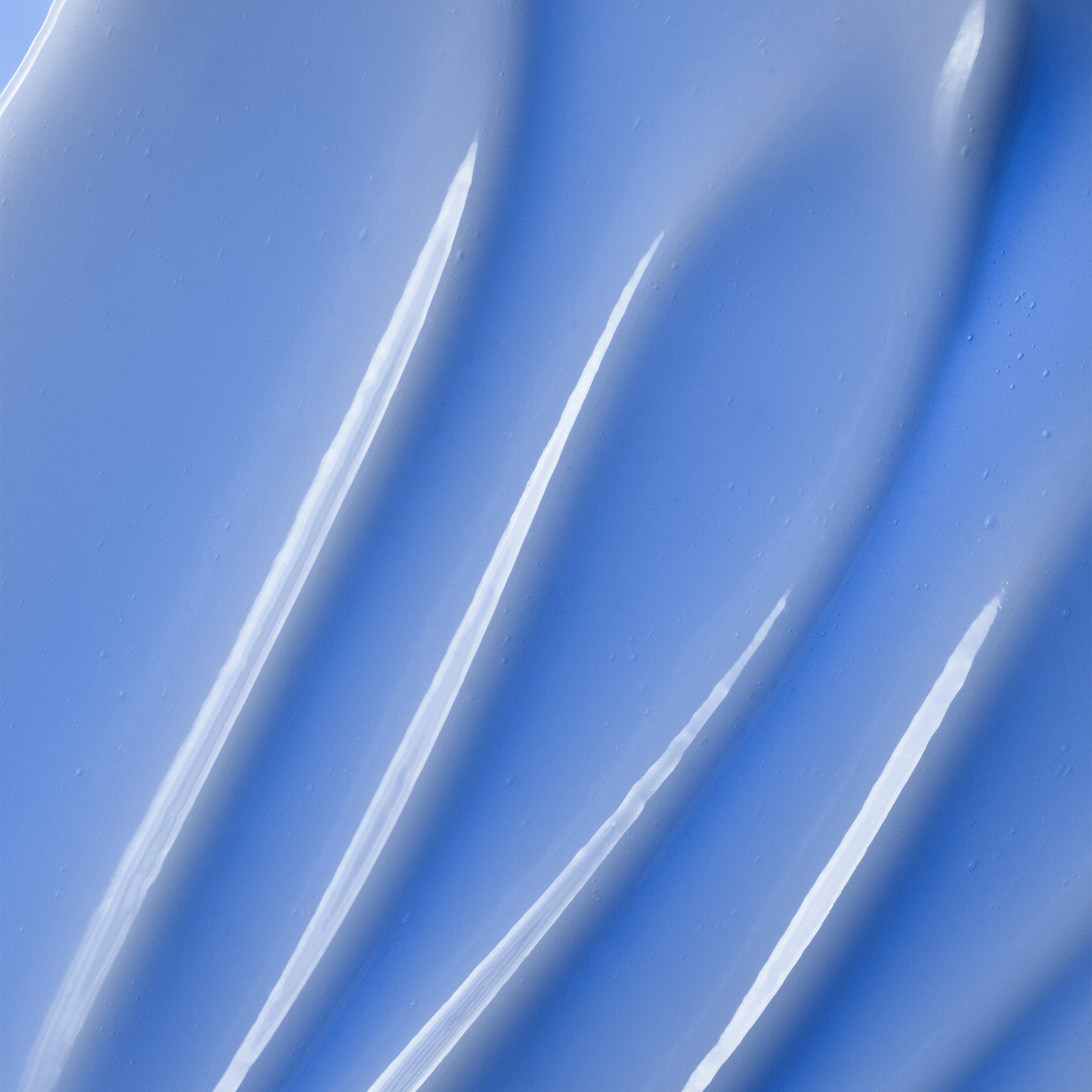 A glossy, light blue skincare cream with curved, textured swirls.
