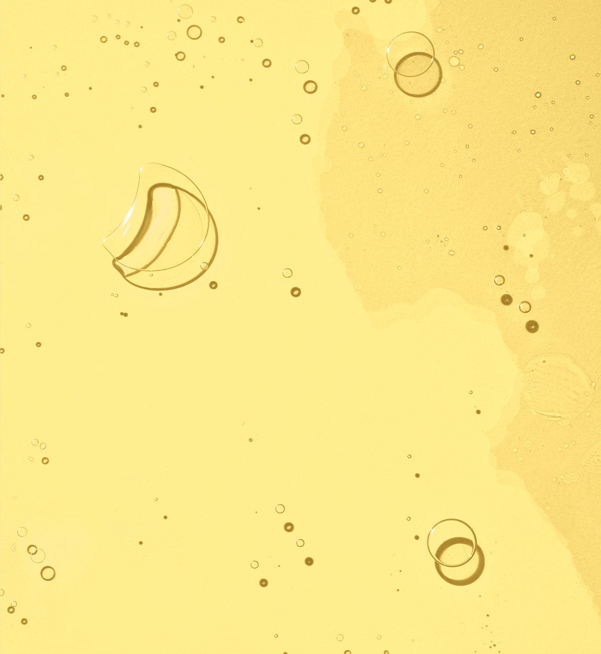A smooth, golden skincare oil texture with bubbles.