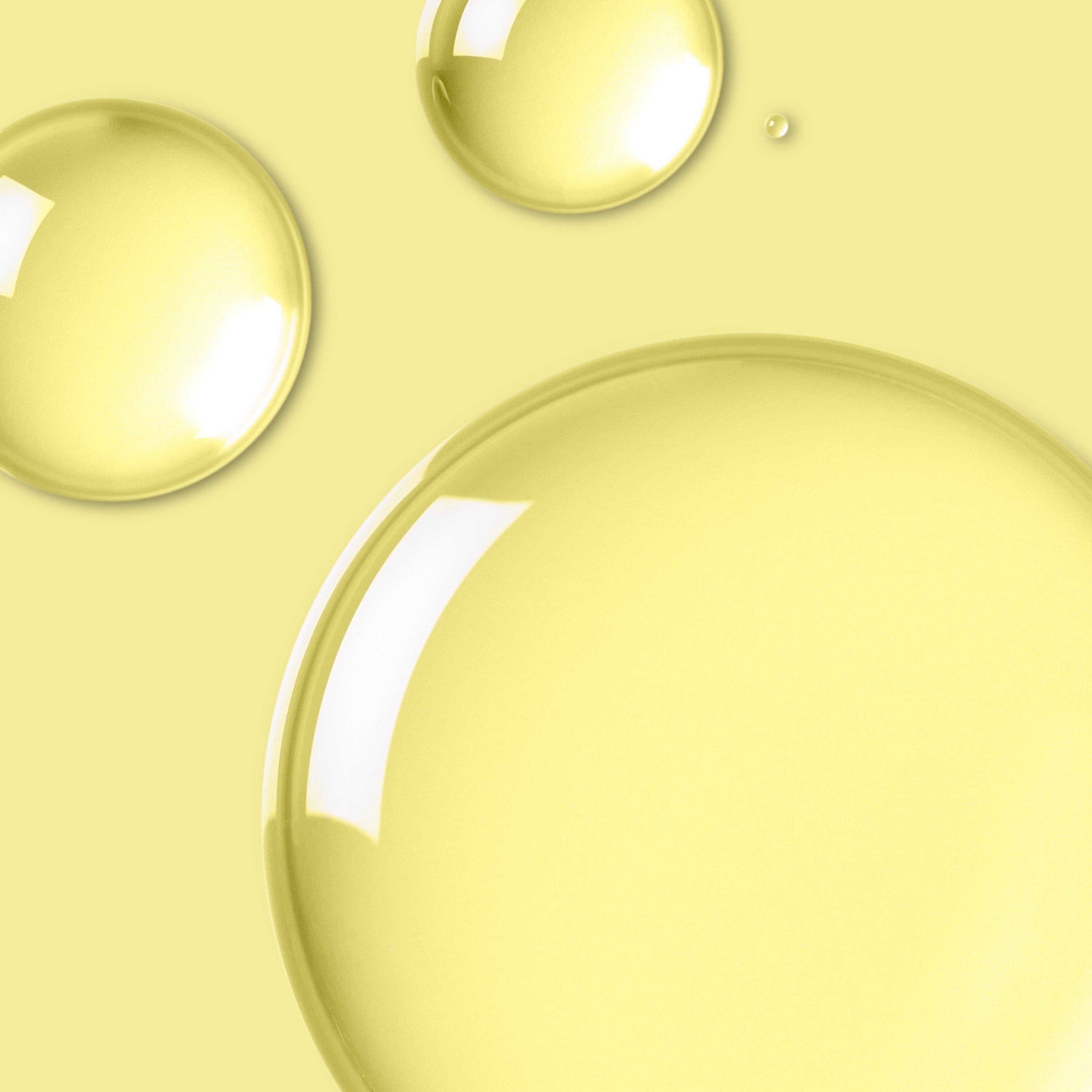 Close-up of translucent skincare oil droplets on a yellow background.