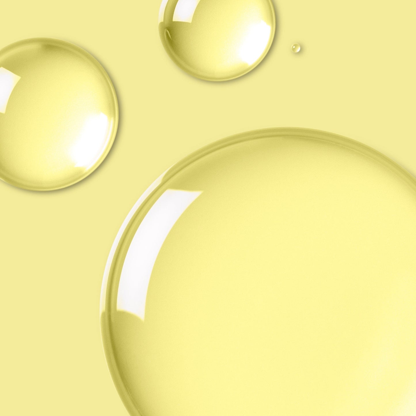 Close-up of translucent skincare oil droplets on a yellow background.