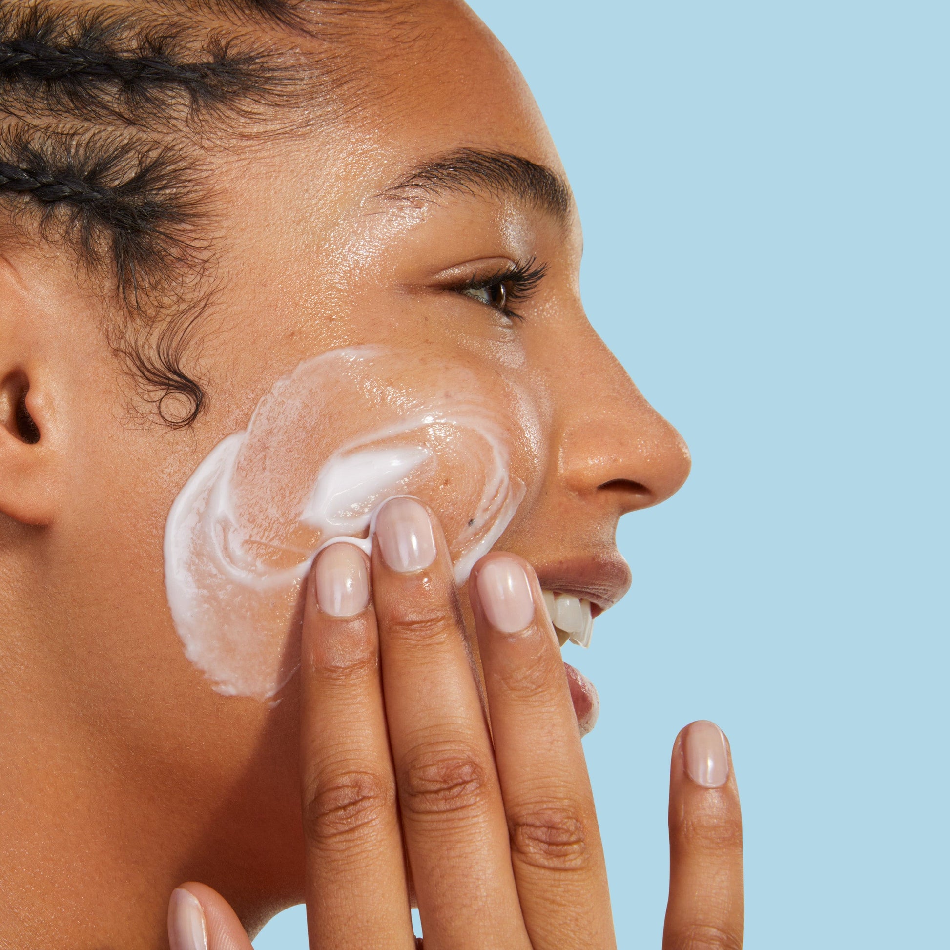 A person applying moisturizer to their face.