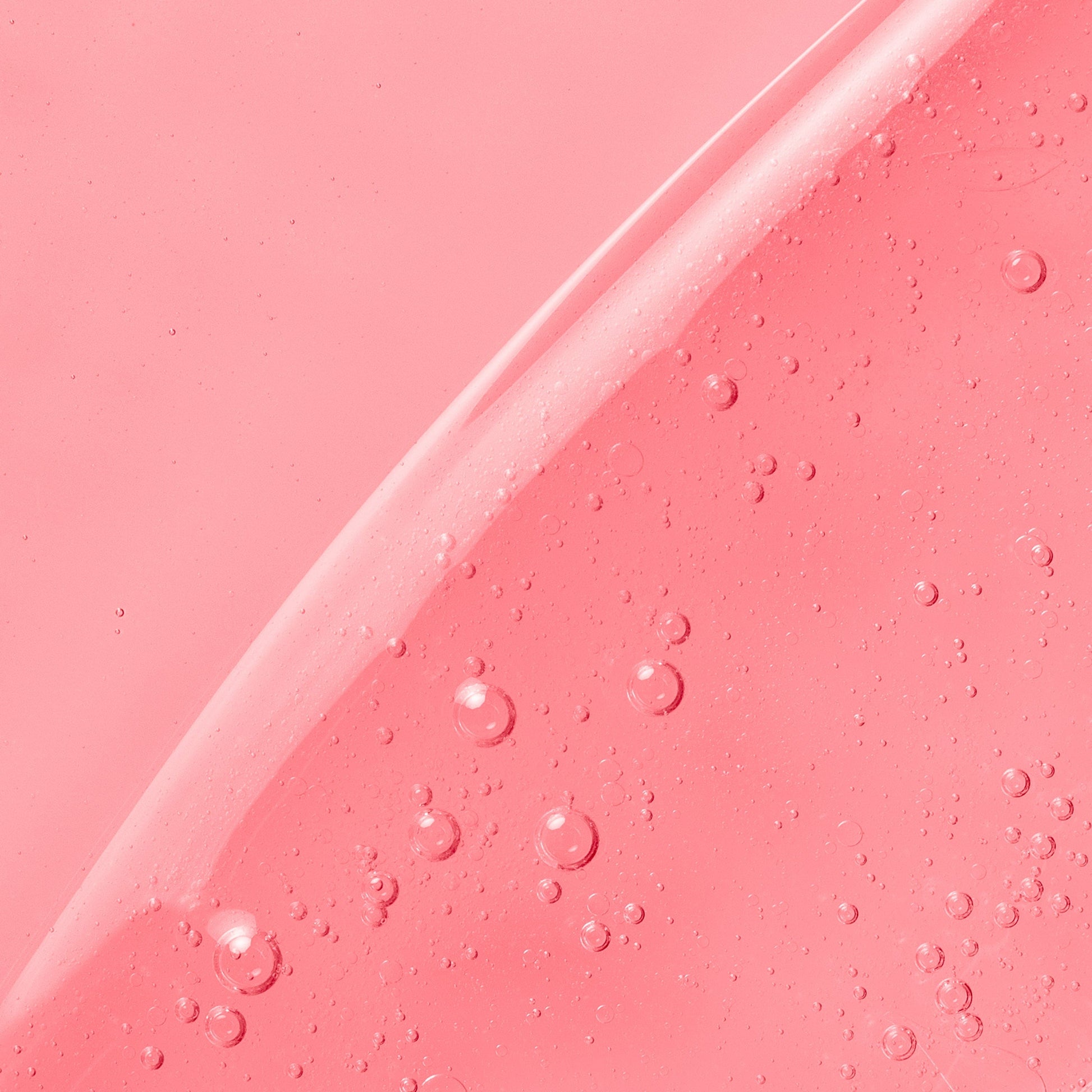 A pink gel-like skincare product with tiny bubbles, creating a glossy appearance.