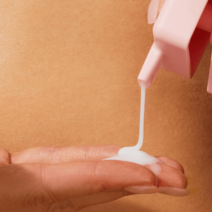 Closeup of a person squeezing skincare product onto her hand.